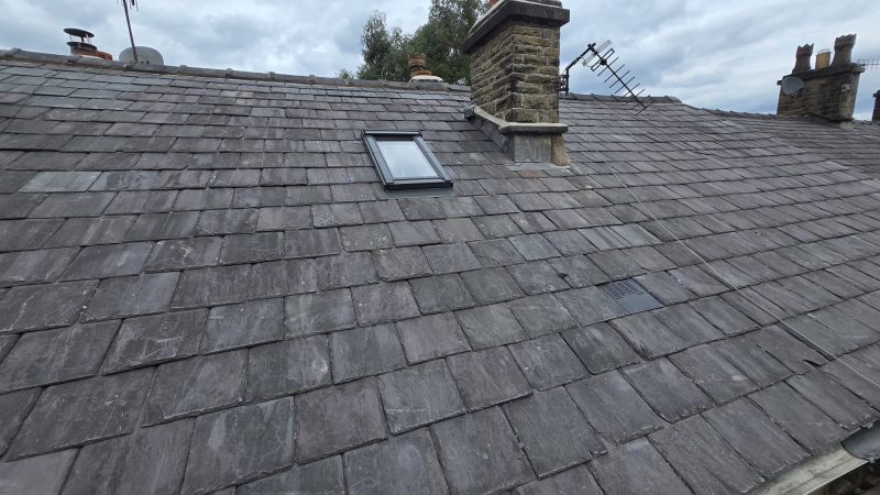 Natural slate roof with a Velux roof window and stone chimney in Wilmslow