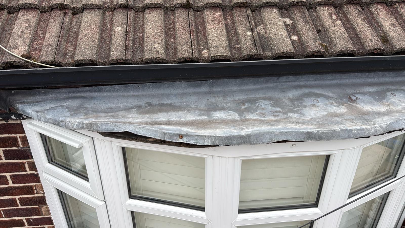 Failed lead bay window roof in Cheadle Hulme, original lead lifting and splitting at the front edge after thermal-movement fatigue