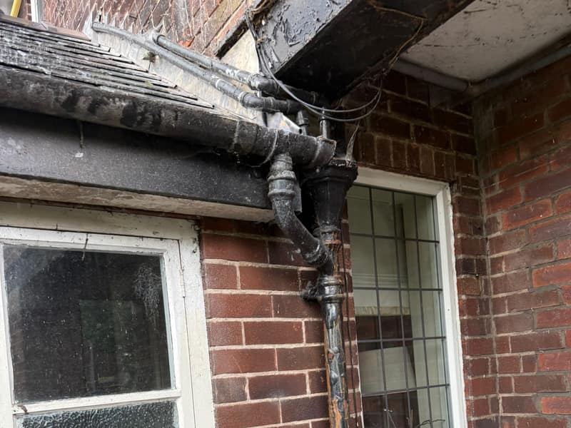 Rotten black timber fascia and corroded cast iron downpipe on an Adlington house before uPVC roofline replacement by Daniel Scott Roofing