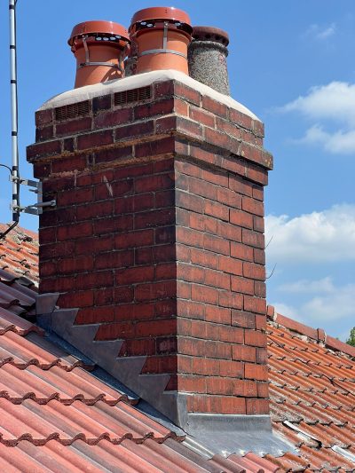 Red brick chimney with fresh flaunching and new stepped lead flashing on a Stockport pantile roof