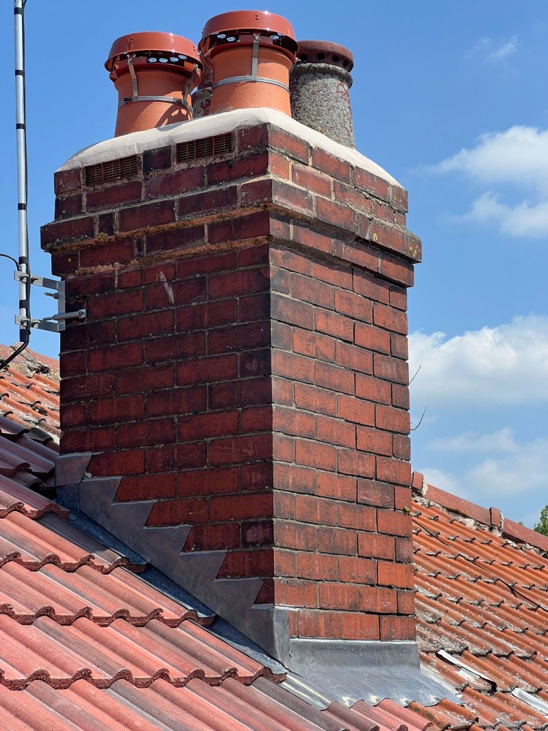 A roofer repairing flaunching and lead flashing on an older Stockport roof